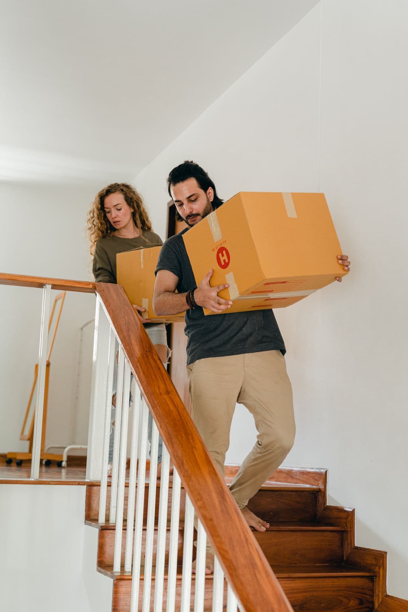 A couple carrying moving boxes through their home, ready for the next chapter